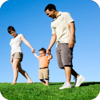 A young boy holding hands with his parents while walking